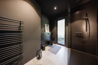 Dunkles Bad mit Handtuchheizkörper, Wand-WC und bodengleicher Dusche
